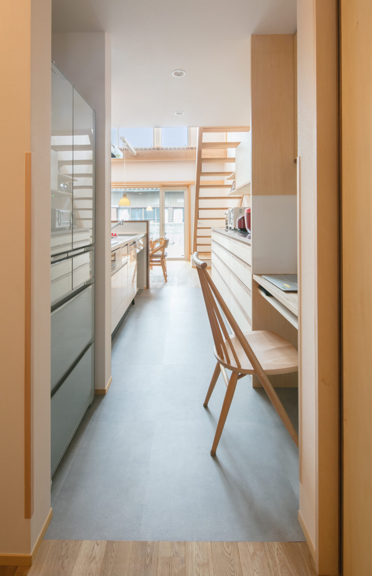 水や汚れに強いグレーのフロアタイルを採用したキッチンスペース。ダイニングからリビングへと視線が抜け、家事をしながらでも家族の気配を感じられる設計です。