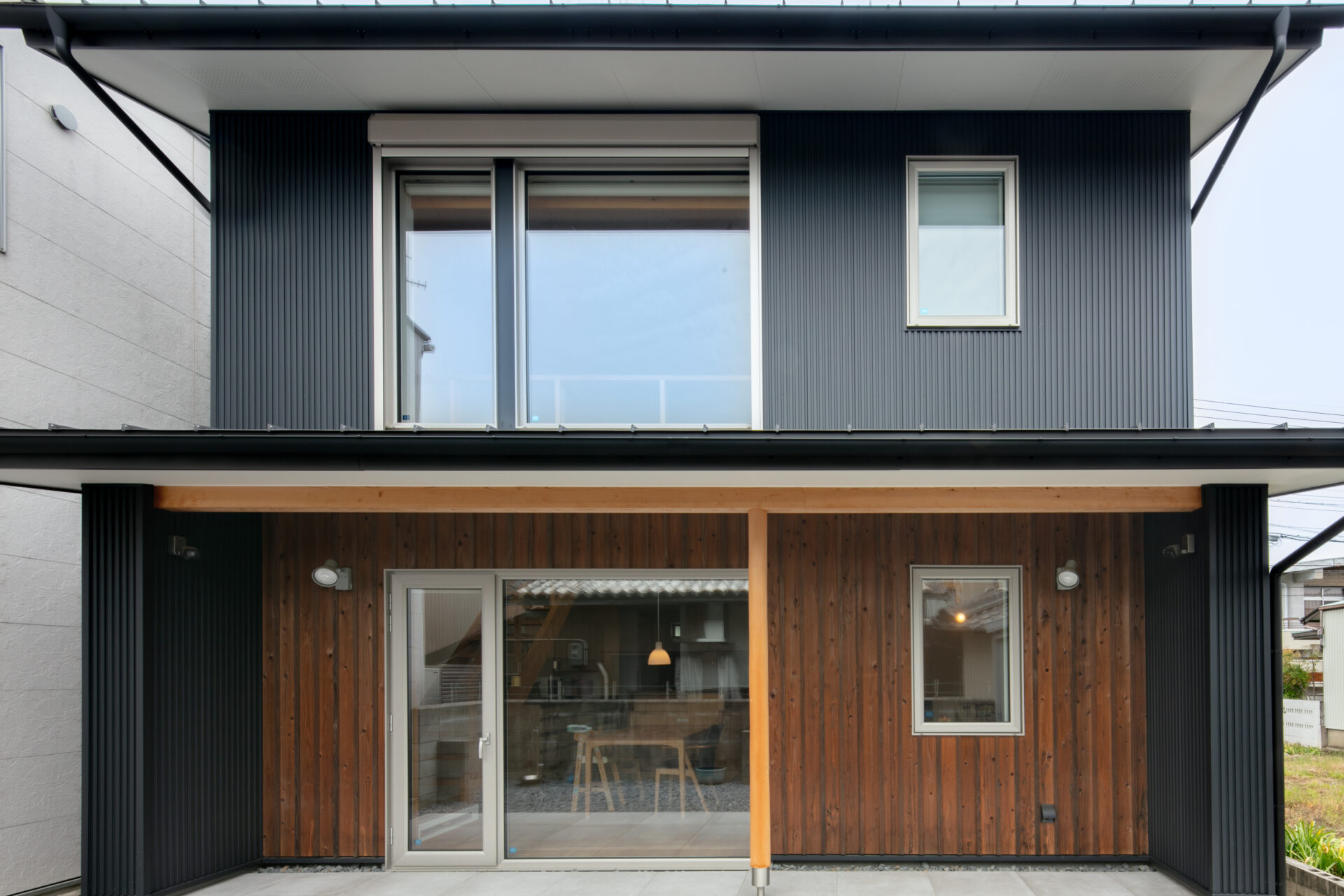 **UA値0.25**の超高性能外皮。黒のガルバリウムと無垢の板張りが調和した外観。南面の窓配置を計算し、冬の暖かさを逃さないパッシブ設計です。
